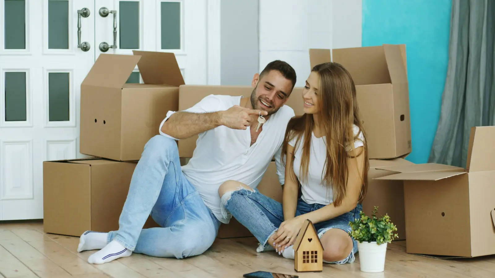 Book international movers early: couple relaxing among packed moving boxes in their new home