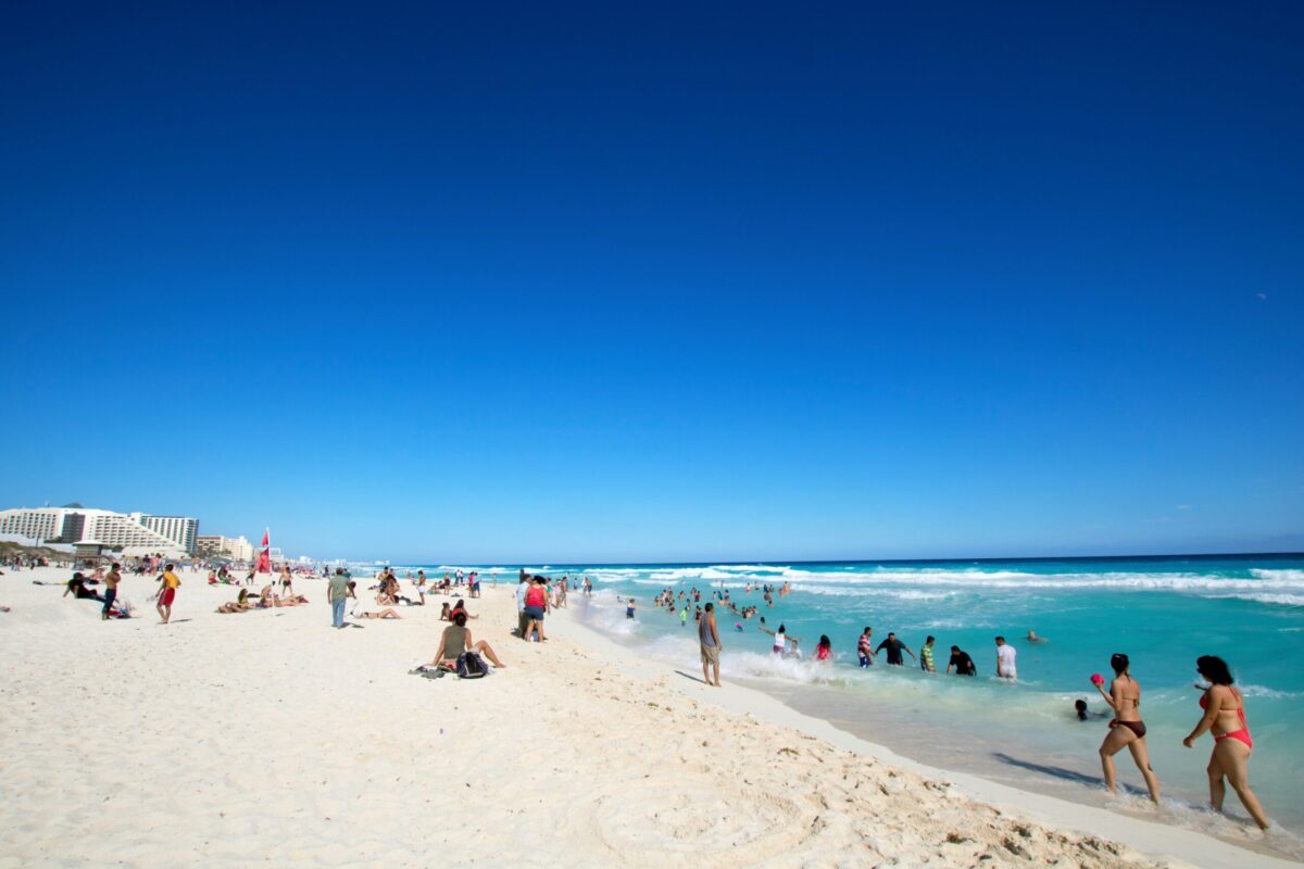 People enjoying the white sandy beach and turquoise Caribbean waters in Cancún, Mexico
